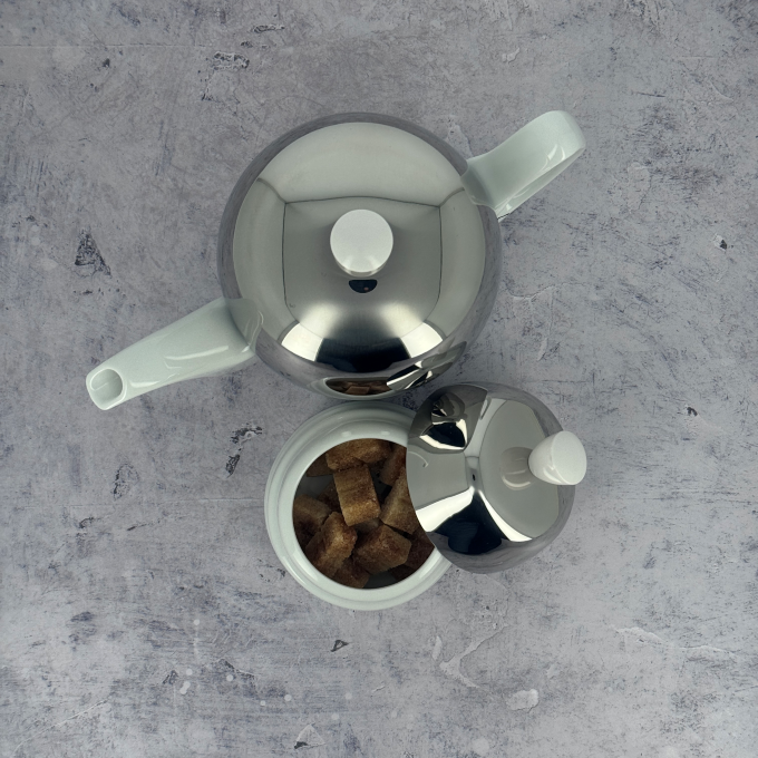 Salam white porcelain sugar bowl and teapot by Degrenne, shown from above with mirror steel lids, embodying French tableware elegance.